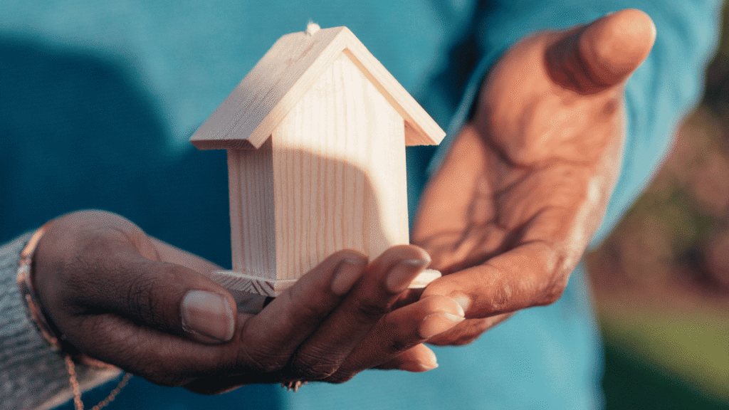 Hands holding a small wooden house, representing Housing Benefit support for people in supported housing
